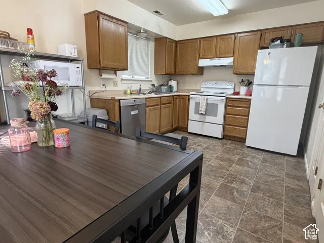 Kitchen featuring wood-finish cabinetry, white appliances, and a light-toned countertop
