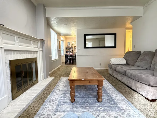Living area featuring a white brick fireplace with a brass firebox, and neutral-toned carpeting