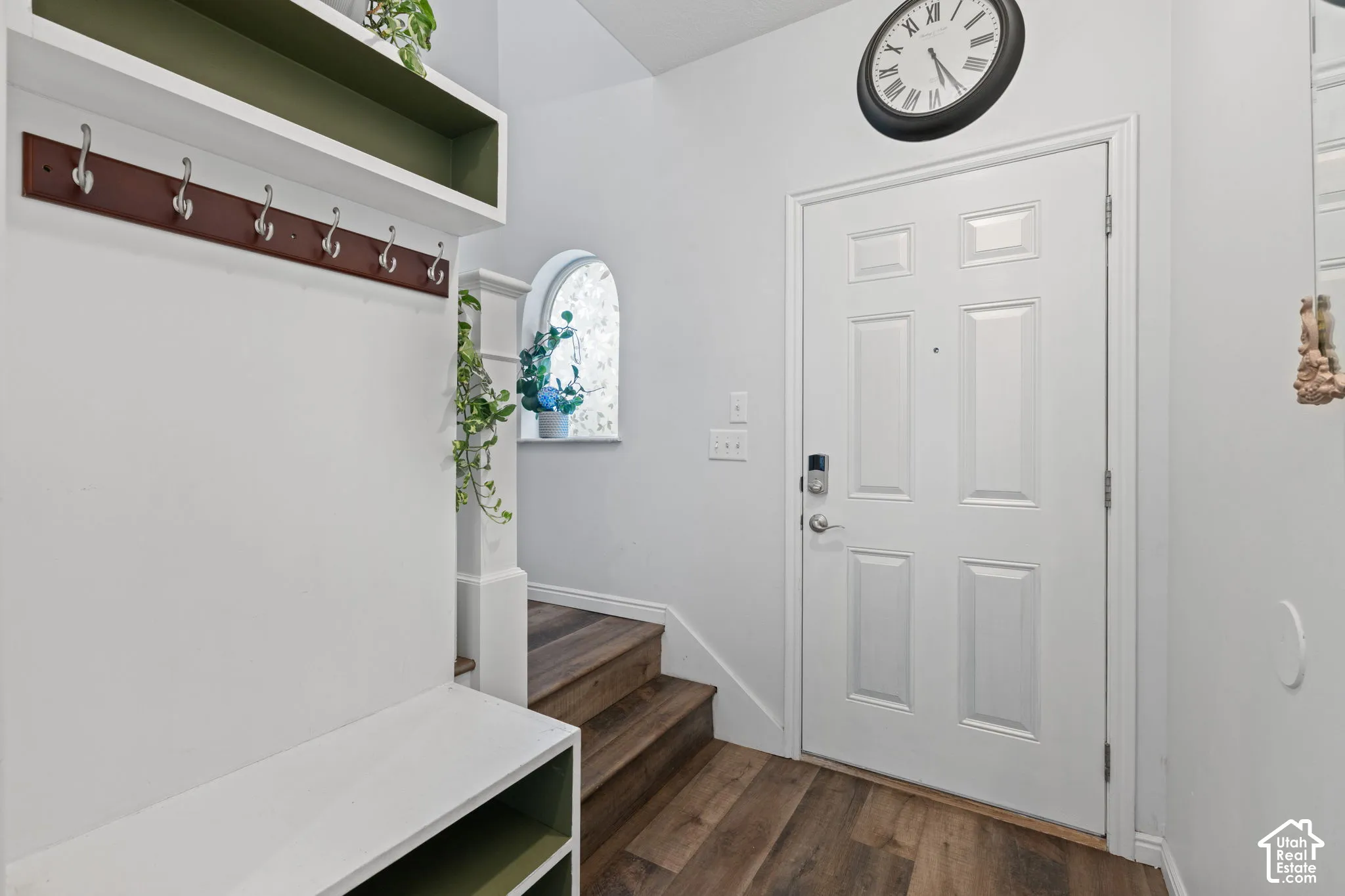 Entryway featuring wood-finish flooring, a paneled door, and a built-in hall tree with storage and hooks