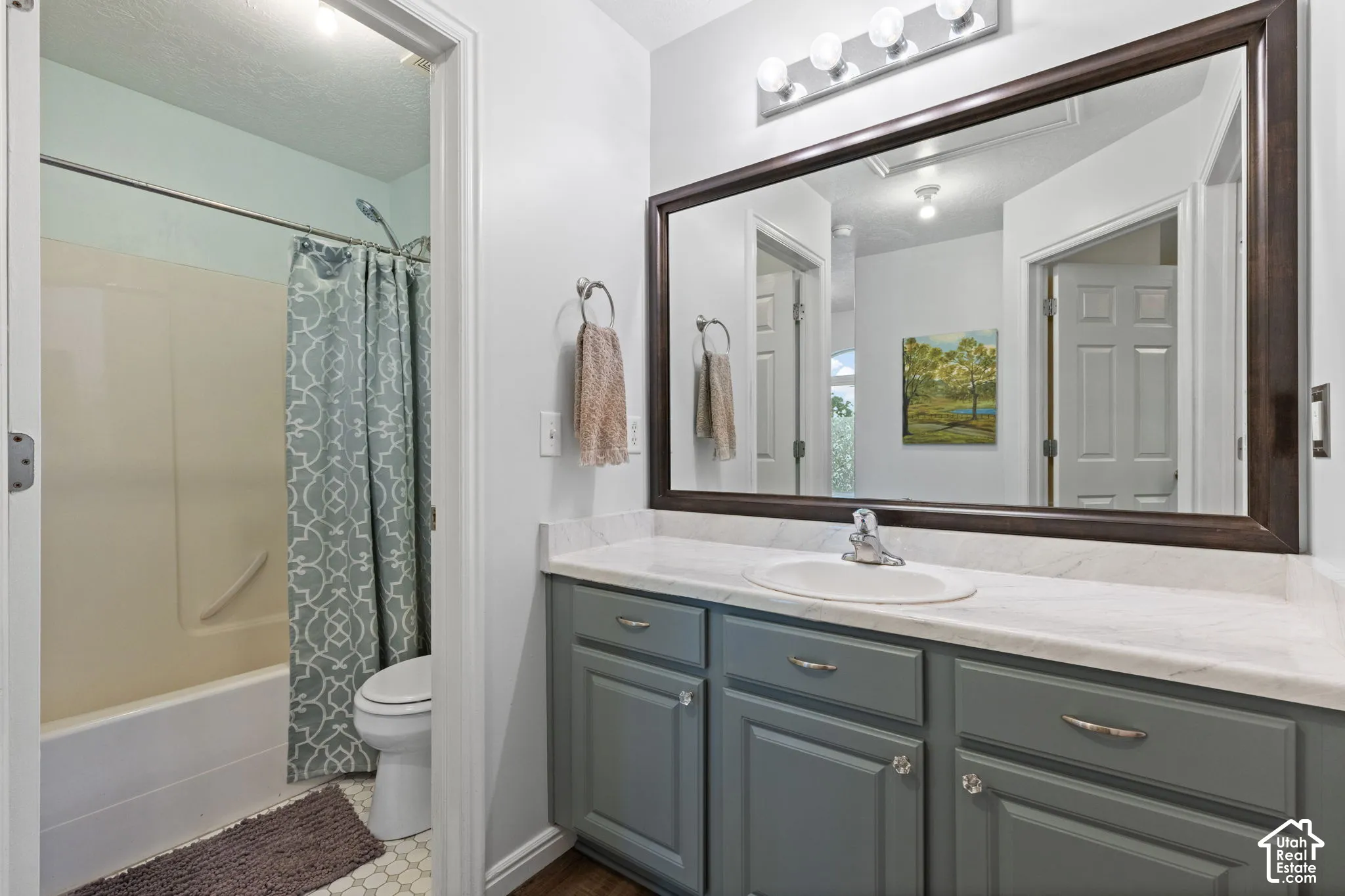 Bathroom featuring a single vanity with gray cabinetry, a white countertop, and a large framed mirror