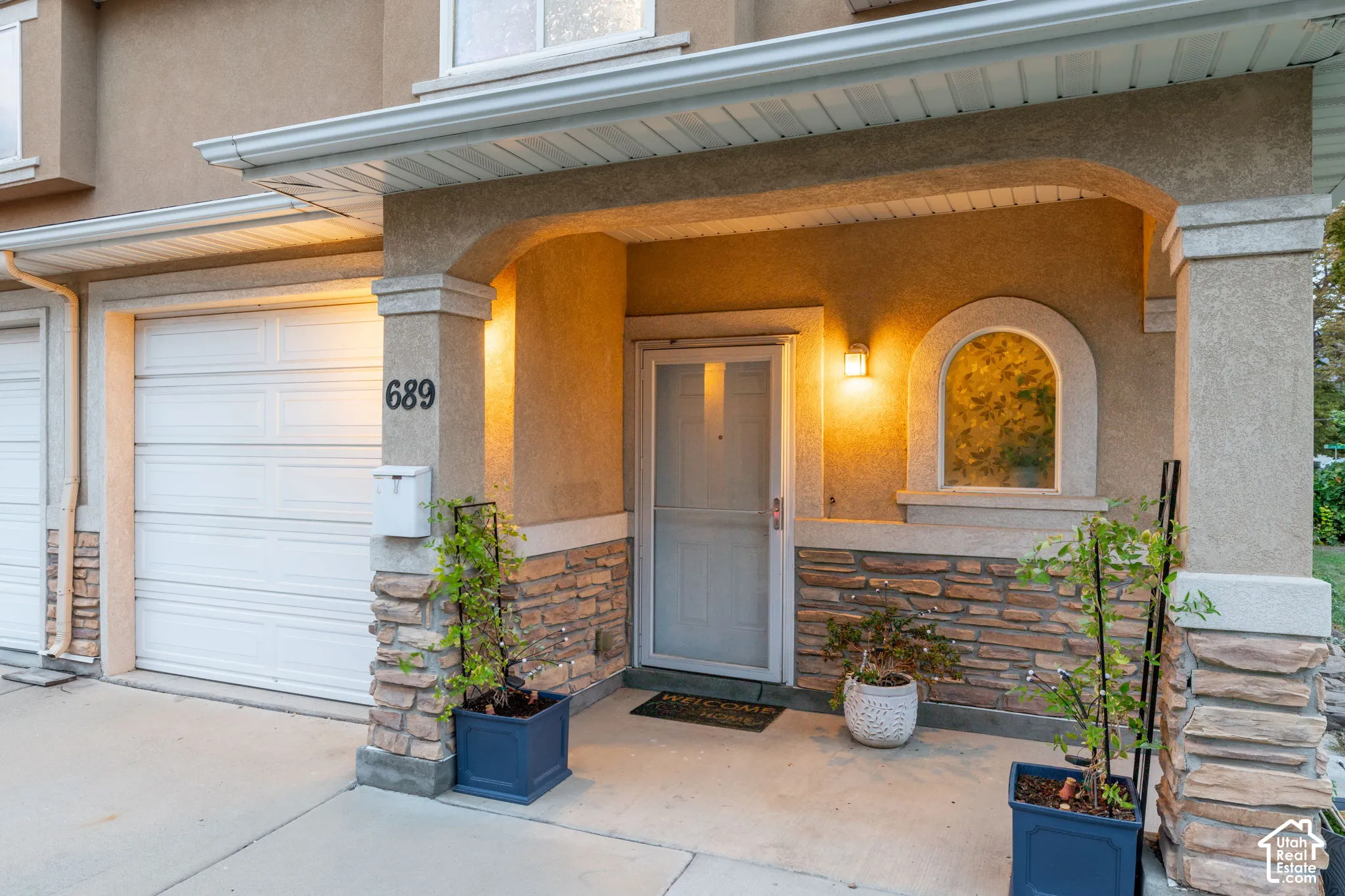 Stucco exterior with stone veneer accents, arched entryway, and an arched window detail