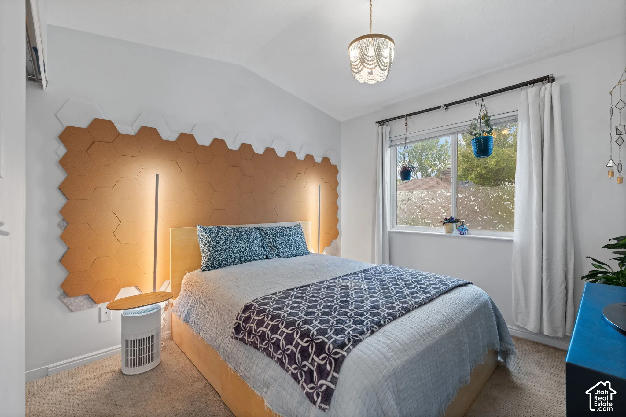 Vaulted ceiling, decorative overhead lighting fixture, hexagonal wall paneling, built-in wall lighting, and window with outdoor scenery