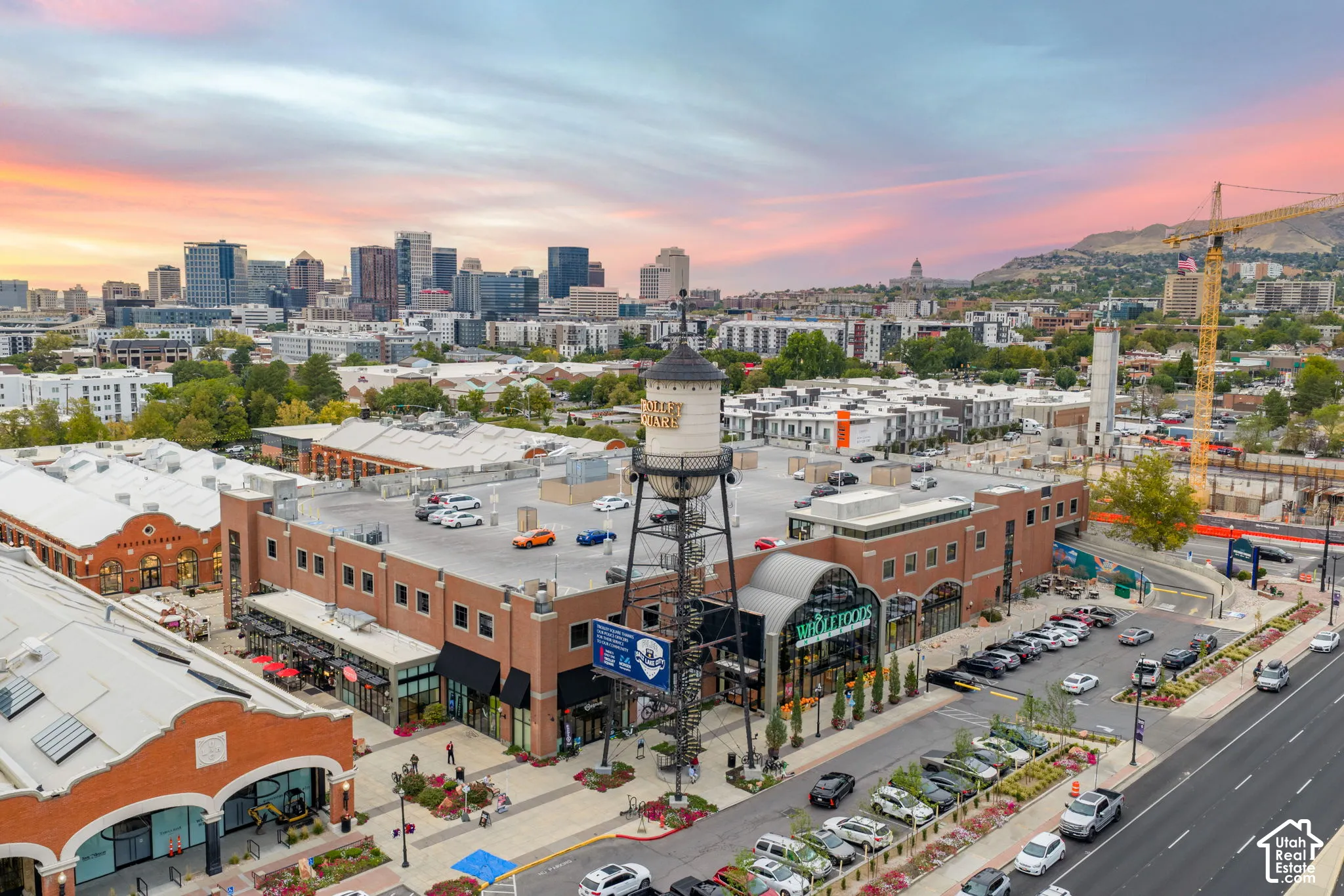 Urban building with brick facade, ground-level retail, rooftop parking, and a prominent water tower feature