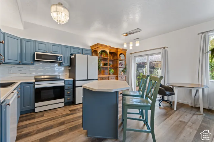 Kitchen featuring blue cabinetry, white countertops, stainless steel appliances, wood-finish flooring, and a sliding glass door