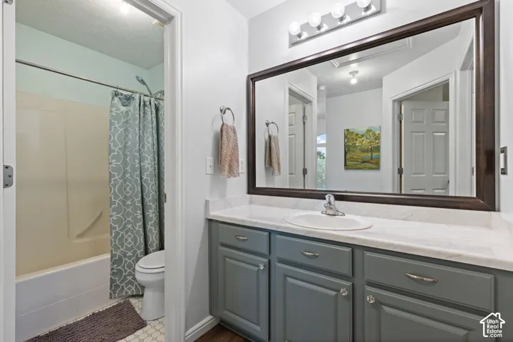 Bathroom featuring a single vanity with gray cabinetry, a white countertop, and a large framed mirror