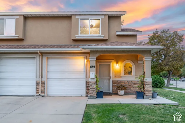 Stucco exterior with stone accents, covered front porch, and two garage doors