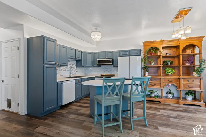 Kitchen featuring deep blue cabinetry, white countertops, tile backsplash, and wood-finish flooring