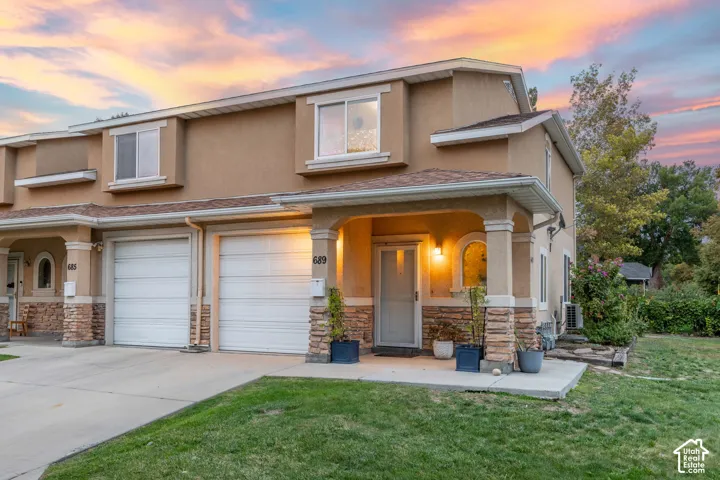 Stucco exterior with stone accents, covered entry, and attached garage
