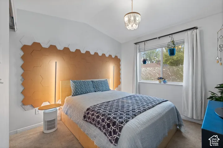 Vaulted ceiling, decorative overhead lighting fixture, hexagonal wall paneling, built-in wall lighting, and window with outdoor scenery