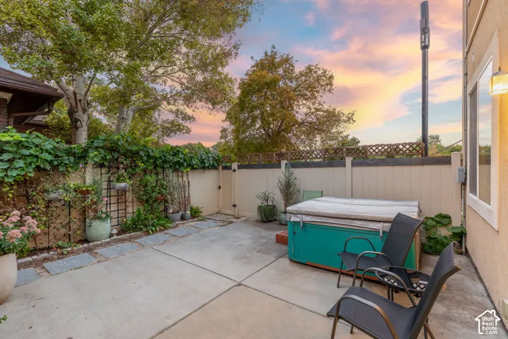 Private patio featuring a built-in hot tub, concrete paving, and a wall-mounted exterior light fixture