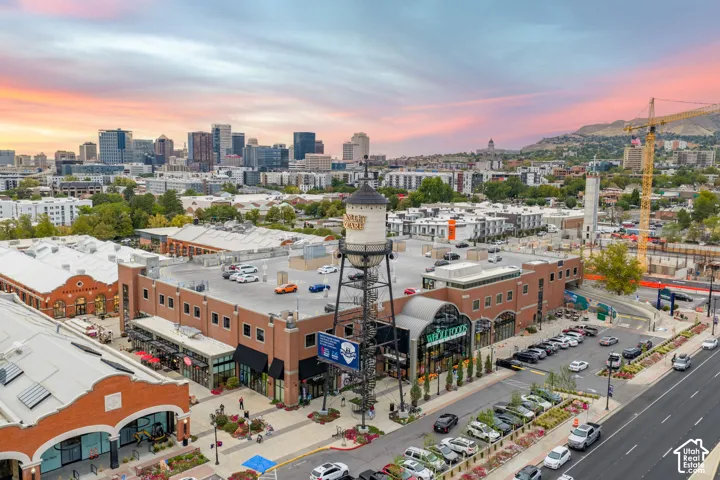 Urban building with brick facade, ground-level retail, rooftop parking, and a prominent water tower feature