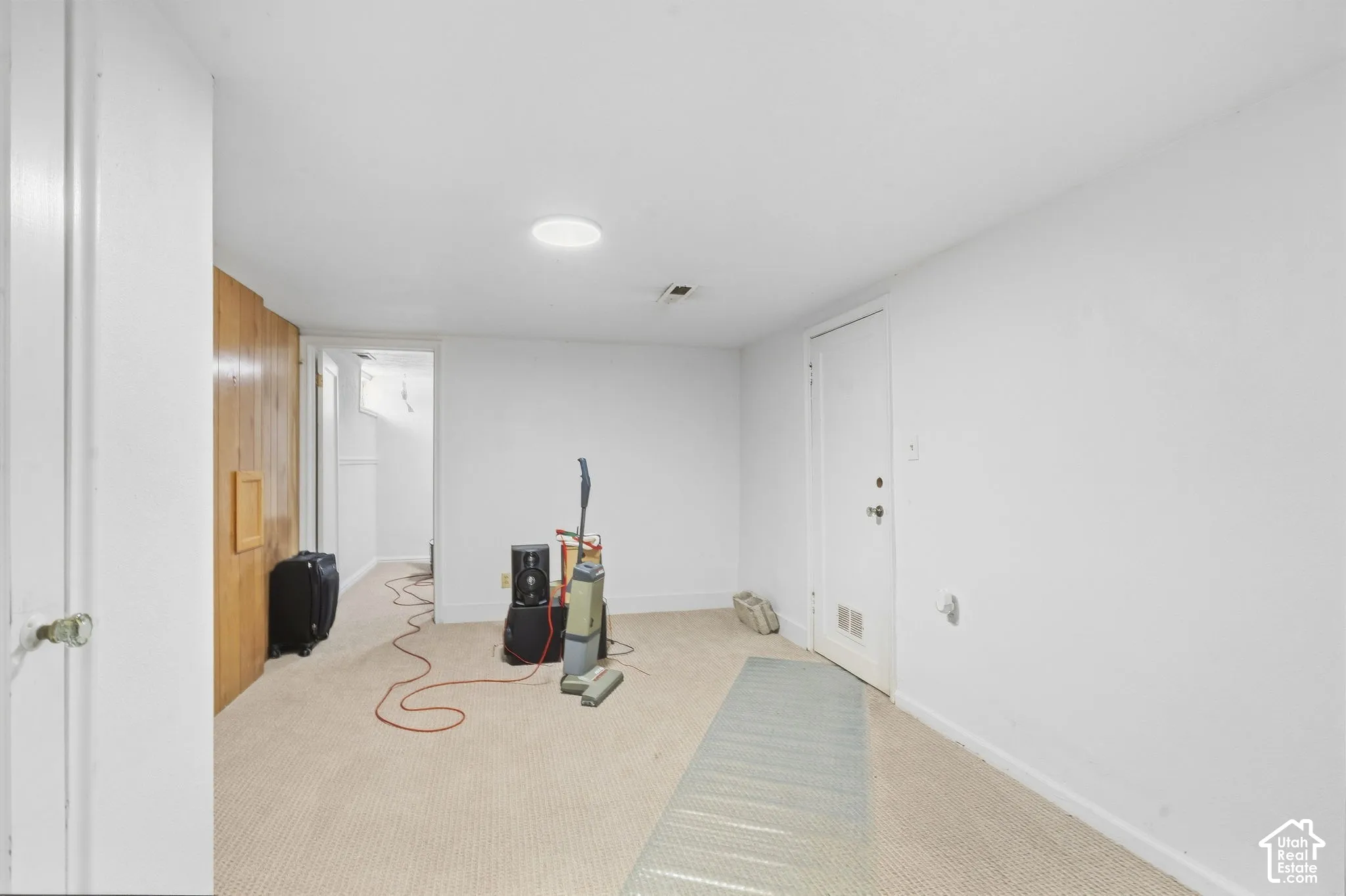 Carpeted flooring, white painted walls, recessed ceiling light, and a wood-paneled accent wall