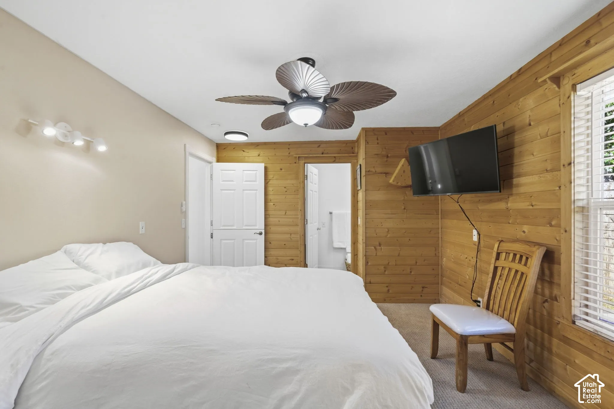 Wood-paneled wall accenting a spacious room with a ceiling fan