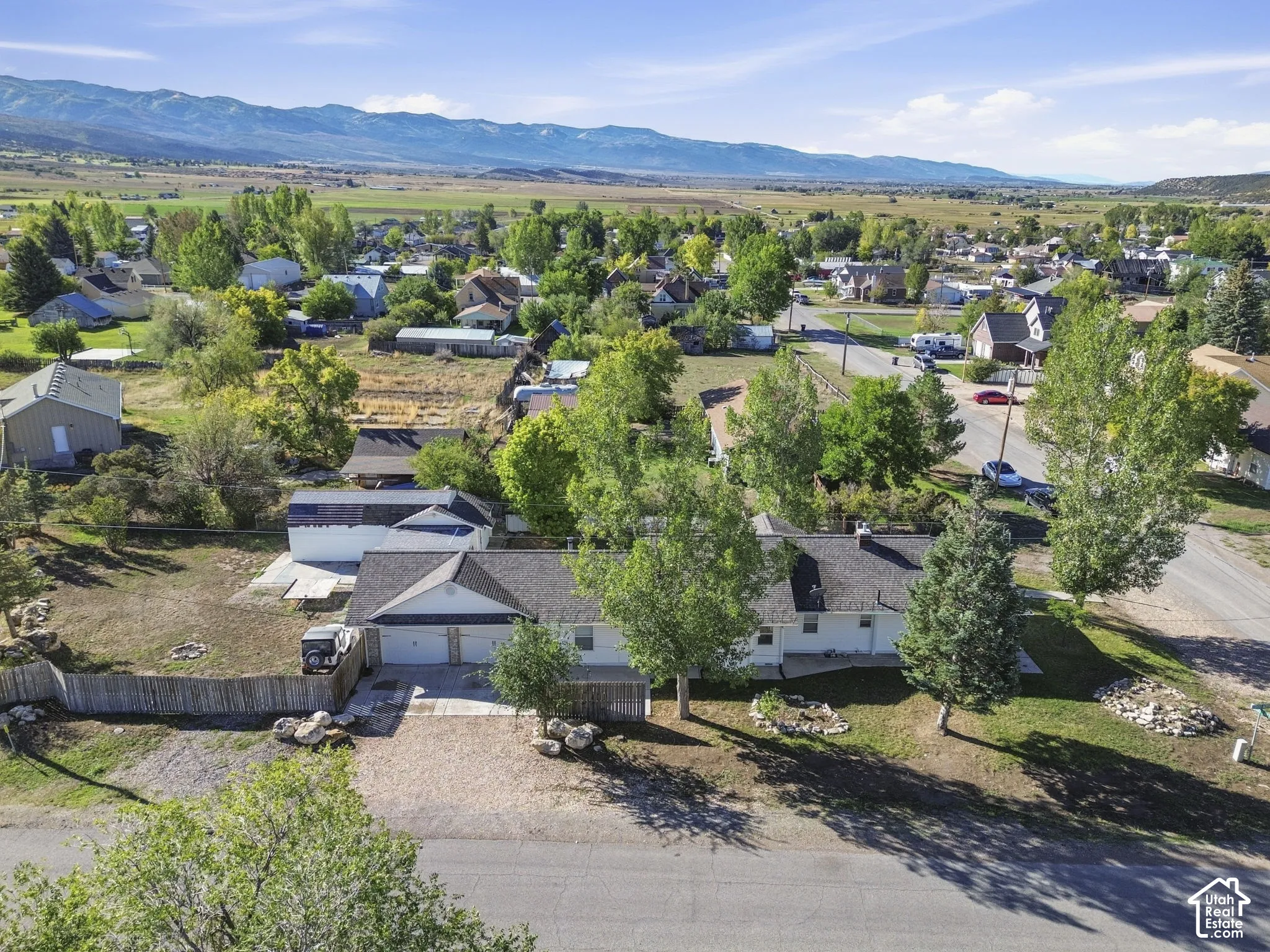 Single-story residence with a two-car garage, pitched shingle roof, and a gravel driveway