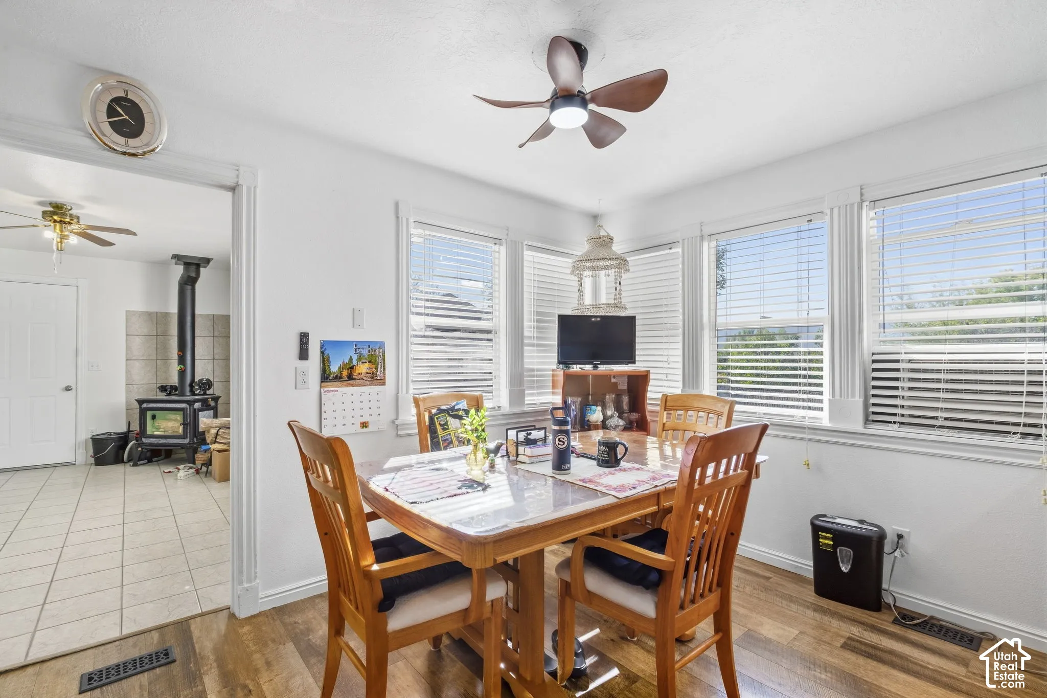 Wood-finish flooring, multiple windows with blinds, and a ceiling fan with integrated lighting
