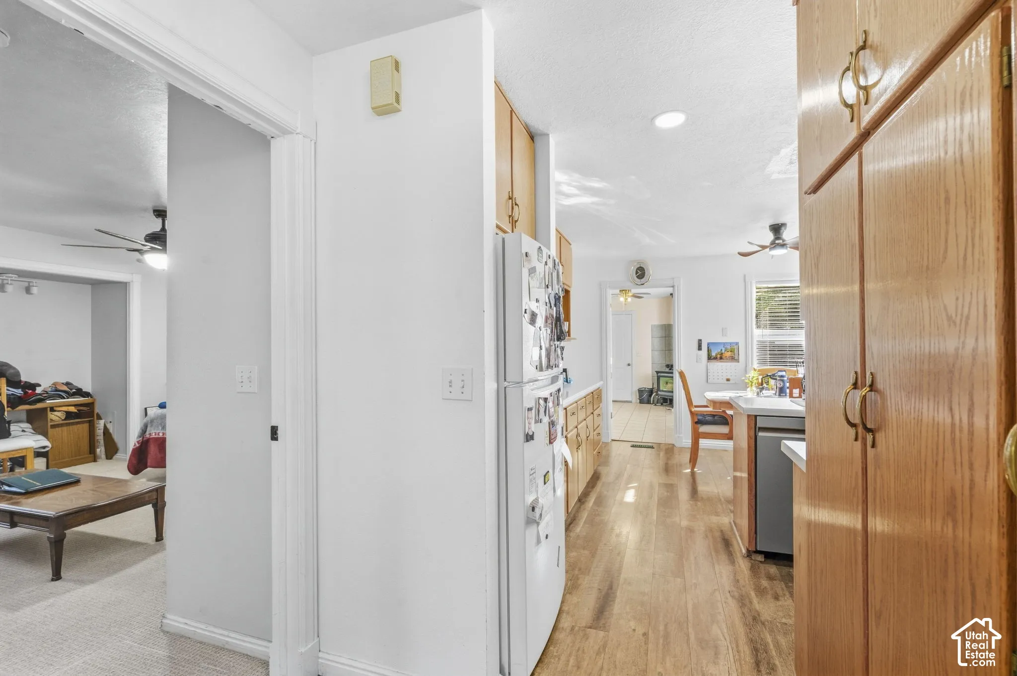 Bright, open kitchen featuring stainless steel appliances, white cabinetry, wood-finish flooring, and abundant natural light from recessed ceiling fixtures