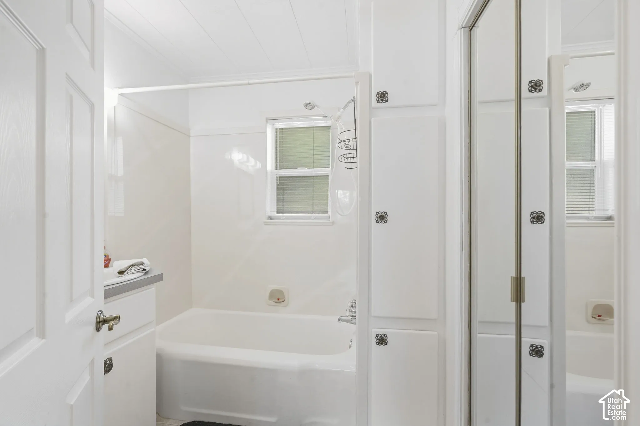 Bathroom featuring a white bathtub, white wall-mounted vanity, and built-in storage cabinetry
