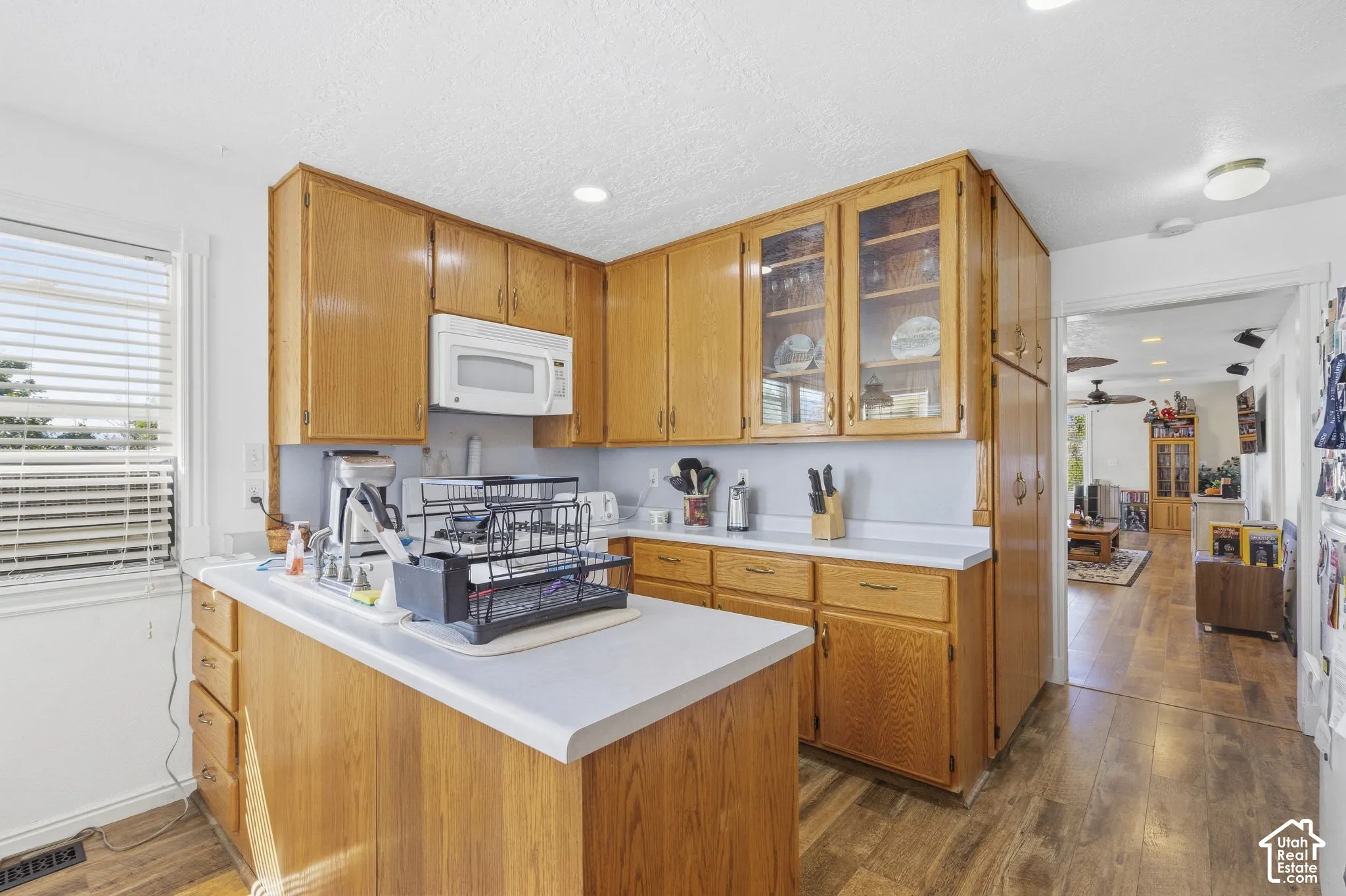 Kitchen featuring wood-finish cabinetry, white countertops, built-in microwave, and wood-finish flooring