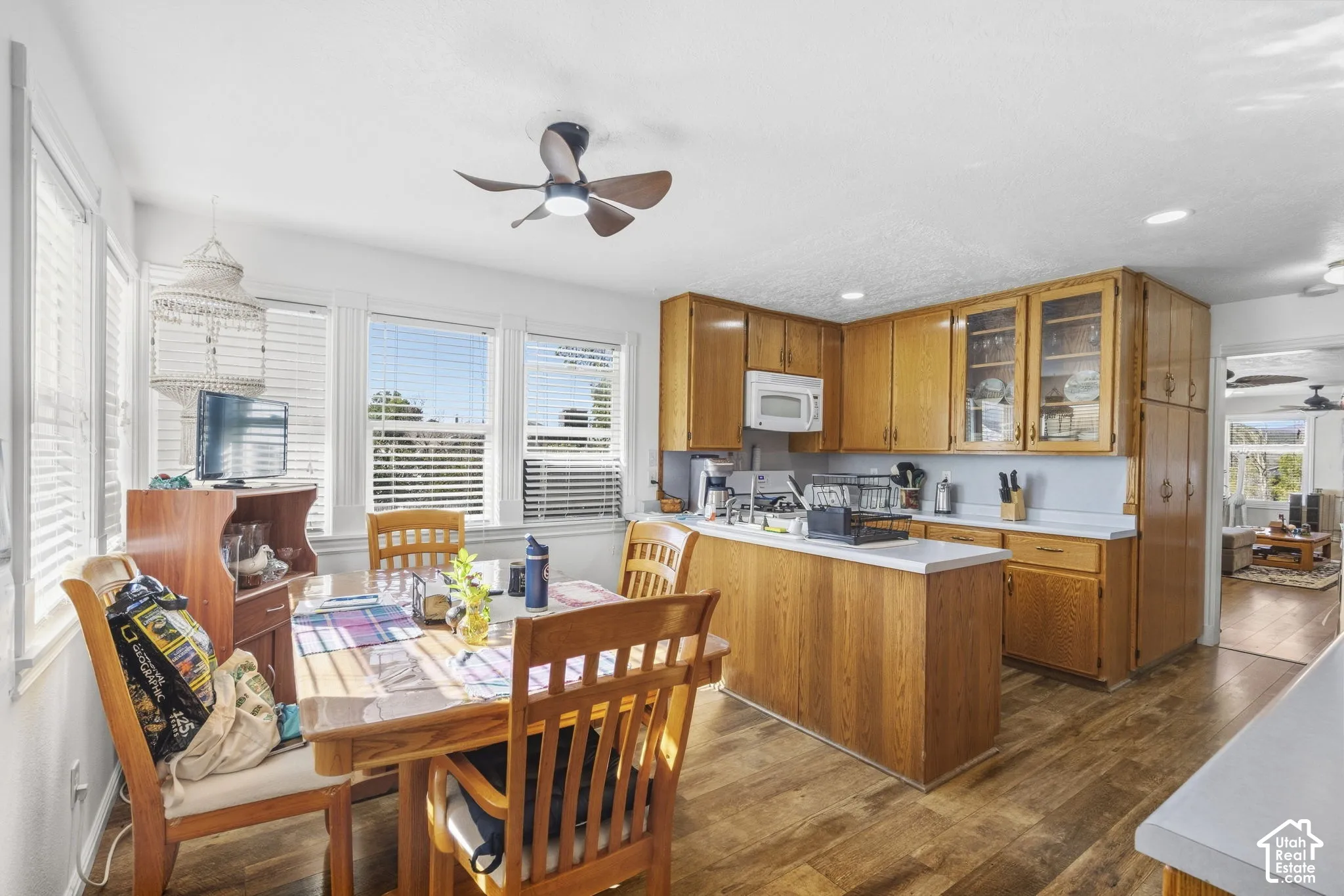 Kitchen and dining area featuring wood-finish flooring, wood cabinetry, white countertops, and multiple windows