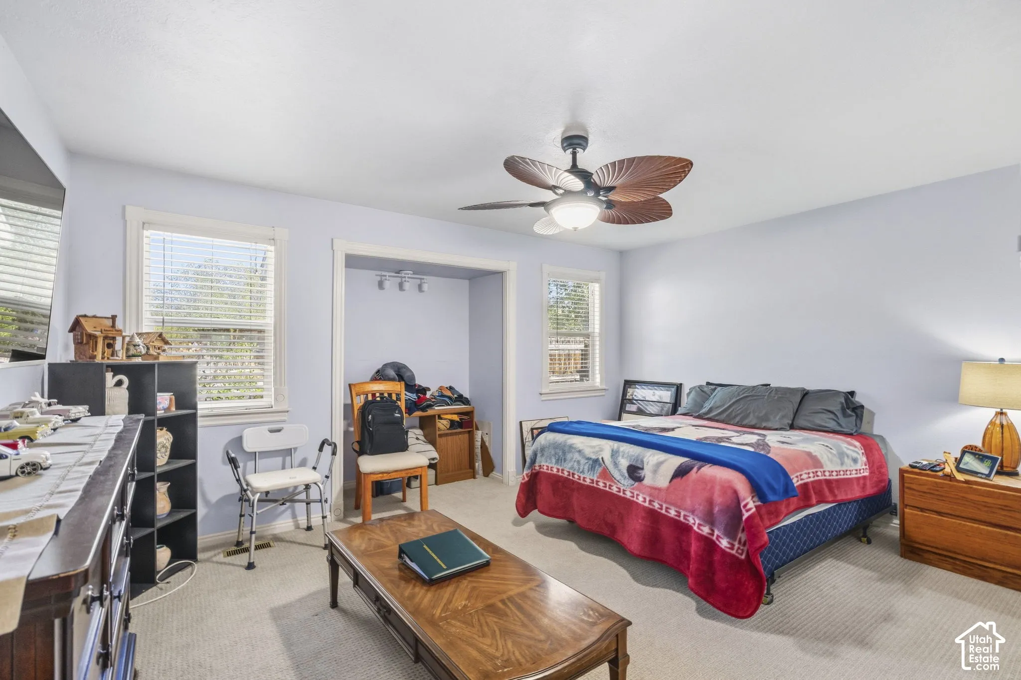 Ceiling fan with light fixture, dual windows with blinds, and light-colored walls
