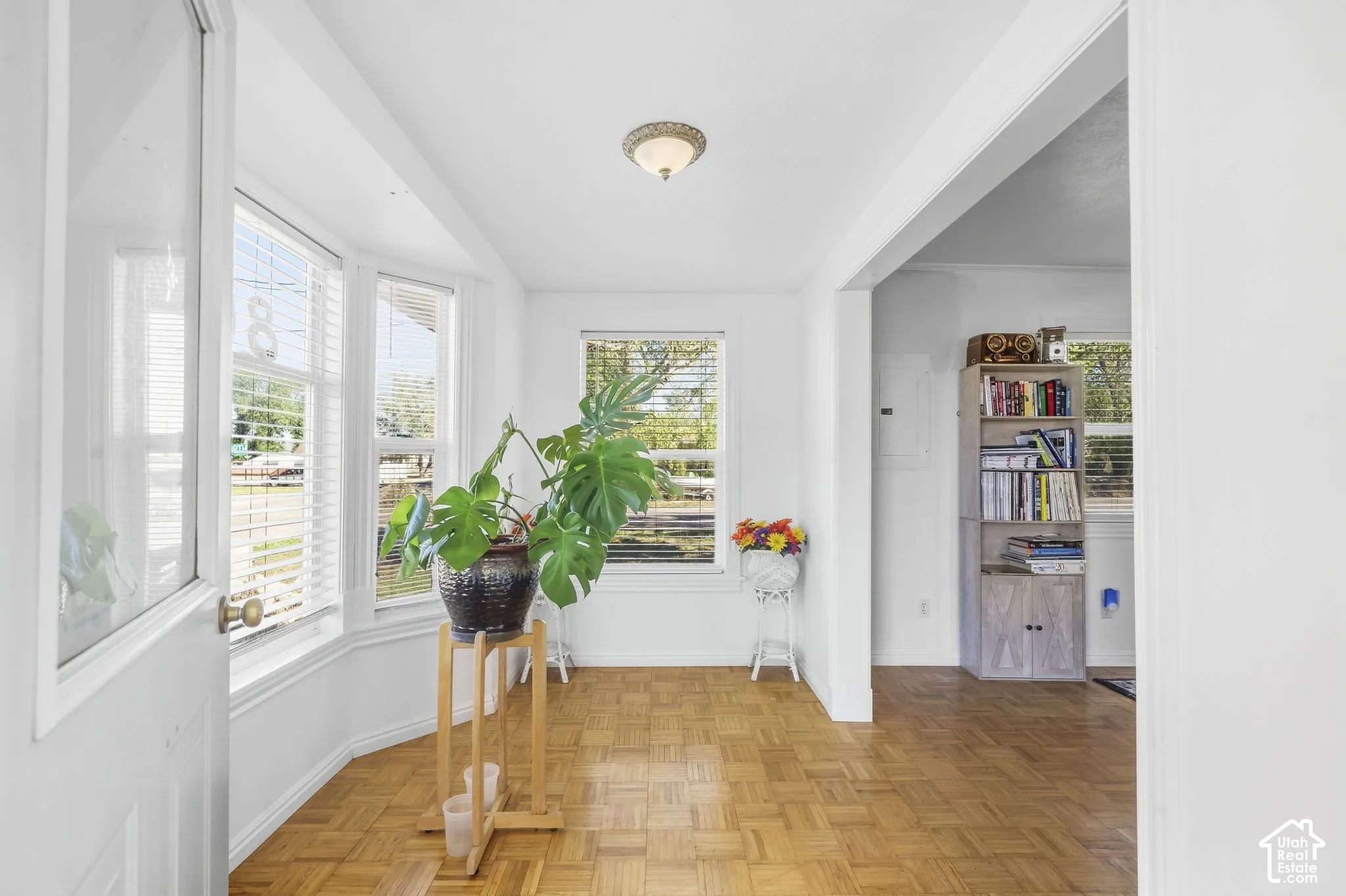 Parquet wood-finish flooring, bay windows with window treatments, a recessed light fixture, and a built-in shelving unit