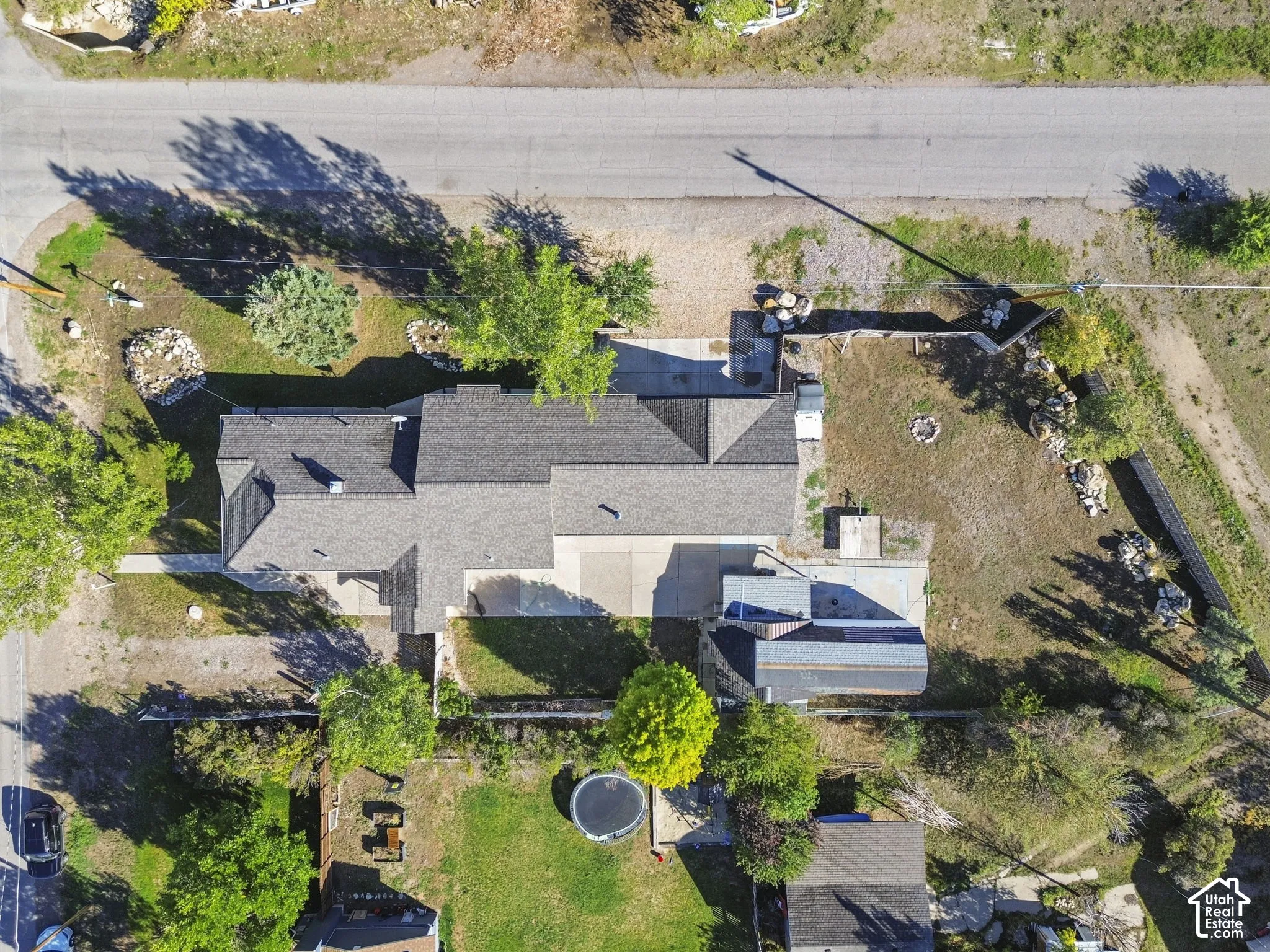 Gabled roofline, asphalt driveway, detached accessory structure, and established trees