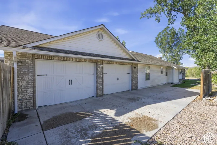 Two-car garage with white paneled doors and decorative hardware, brick accents, and a concrete driveway