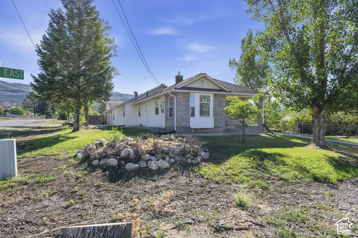 Brick and siding exterior featuring a bay window, mature trees, and a sloped lawn