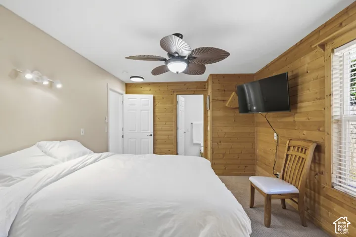 Wood-paneled wall accenting a spacious room with a ceiling fan
