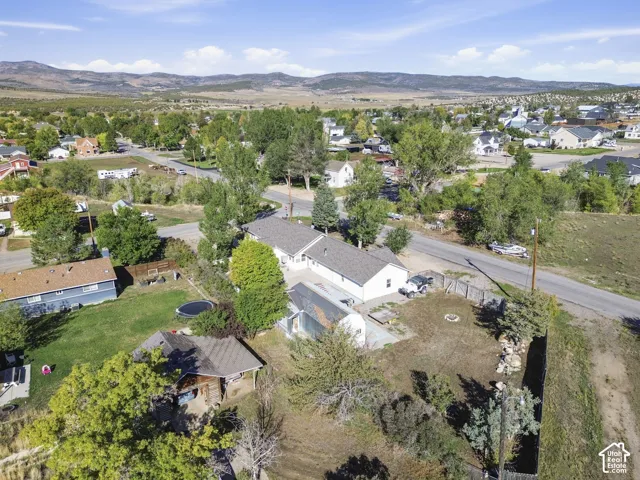 Expansive property featuring multiple structures, mature trees, and mountainous surroundings