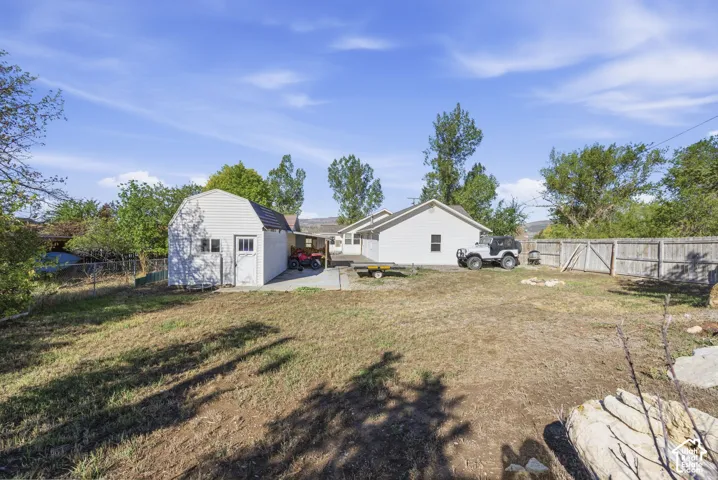Expansive outdoor space featuring a detached storage shed, a paved area, and a wood privacy fence