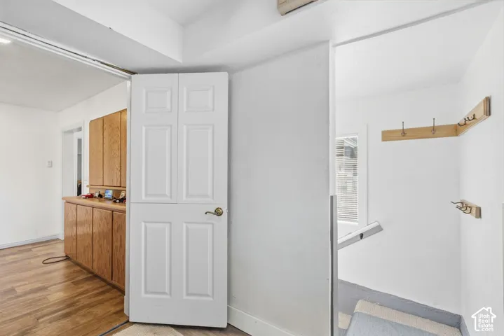 White paneled door opening to a space with wood-finish flooring and built-in wood cabinetry