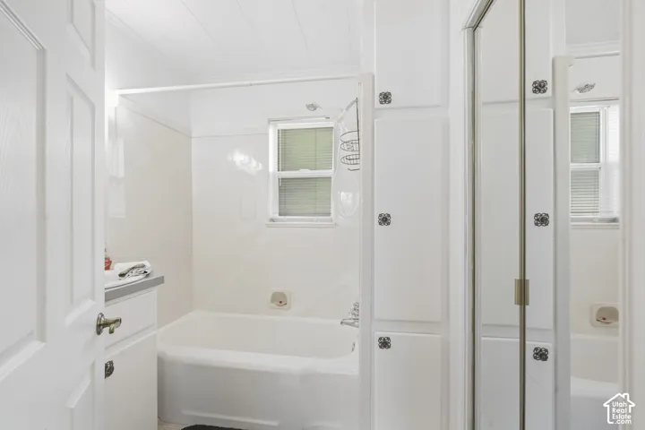 Bathroom featuring a white bathtub, white wall-mounted vanity, and built-in storage cabinetry