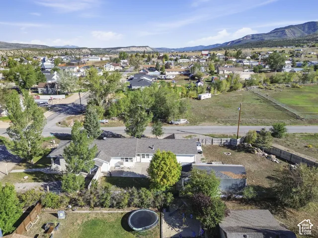 Expansive property featuring a single-story residence, mature trees, and a mountain backdrop
