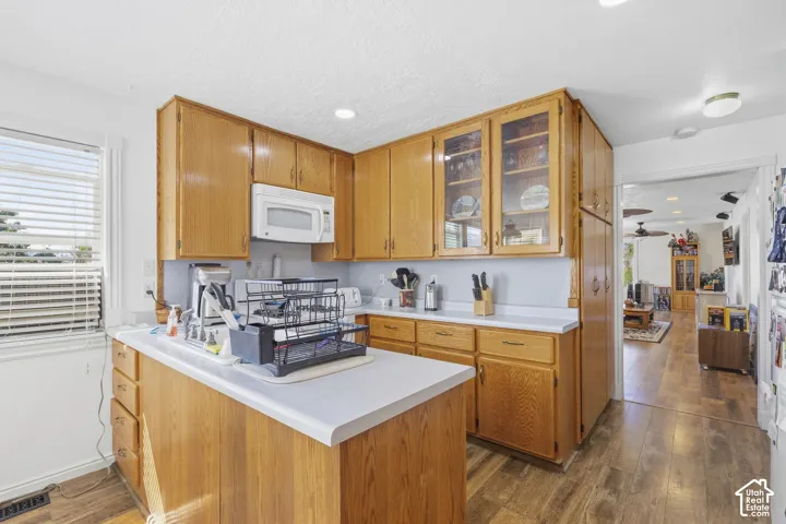 Kitchen featuring wood-finish cabinetry, white countertops, built-in microwave, and wood-finish flooring