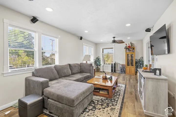Recessed lighting, wood-finish flooring, multiple windows with blinds, ceiling fan with light, and a built-in media cabinet