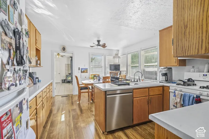 Wood-finish flooring, wood cabinetry, white countertops, and white appliances