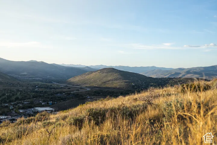 Expansive mountain landscape with a verdant valley, distant hills, and varied natural terrain