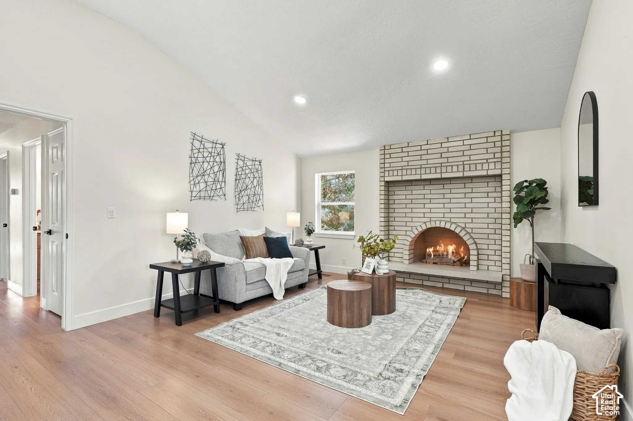 Vaulted ceiling, recessed lighting, wood-finish flooring, brick fireplace, and interior window