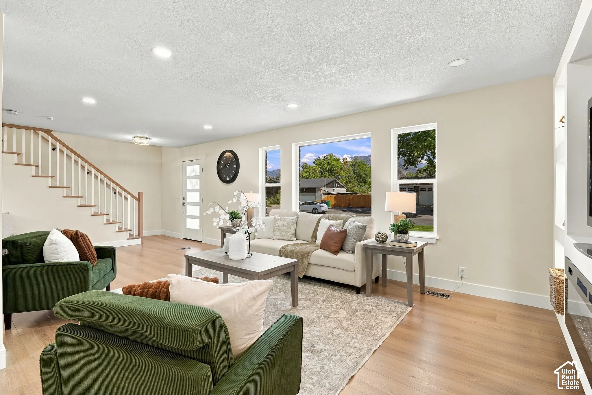 Recessed lighting throughout, wood-finish flooring, staircase with wood handrail and white balusters, multi-pane entry door, and built-in shelving with integrated lighting
