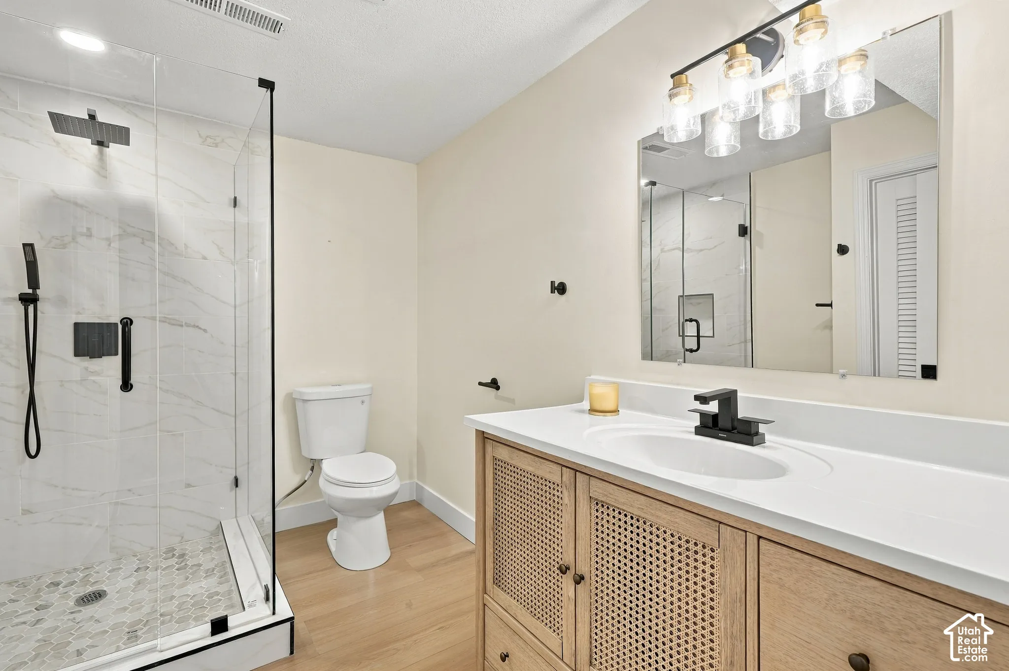 Shower enclosure with clear glass paneling and black trim, large format white tile shower surround, and a pebble tile shower floor