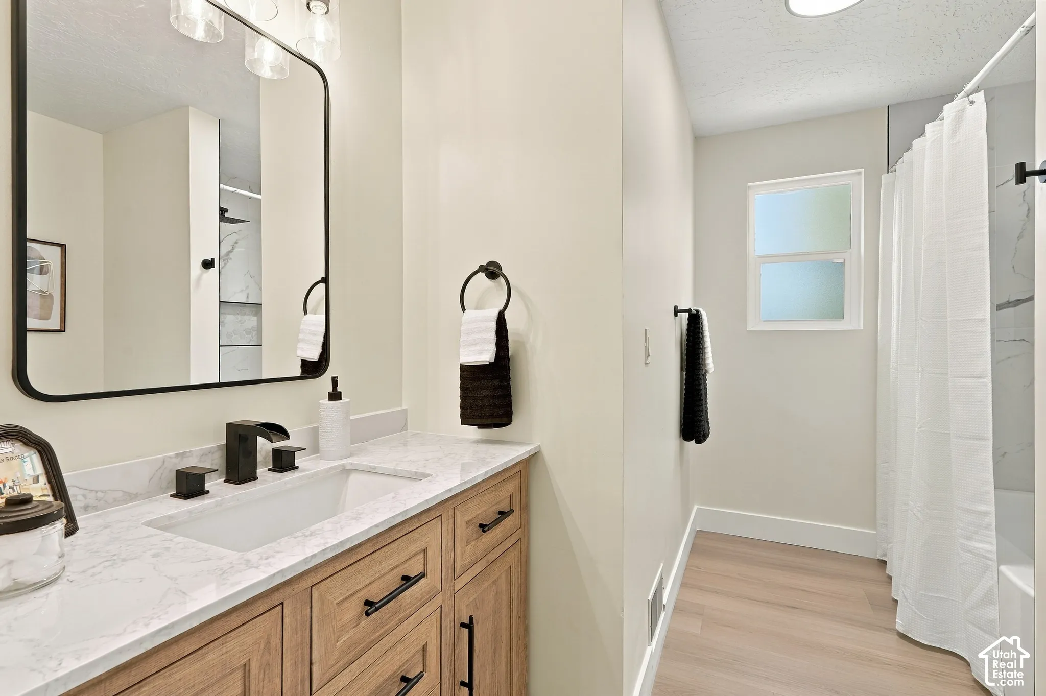 Light wood-finish flooring with a white tub and shower combination