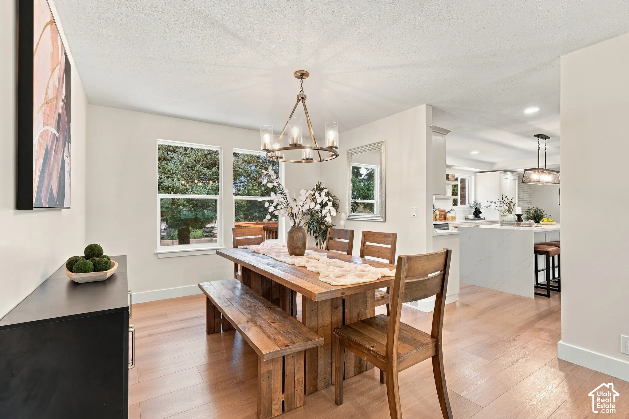 Light wood-finish flooring throughout, multiple windows, and a bronze-finish chandelier