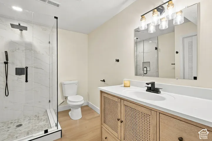 Shower enclosure with clear glass paneling and black trim, large format white tile shower surround, and a pebble tile shower floor
