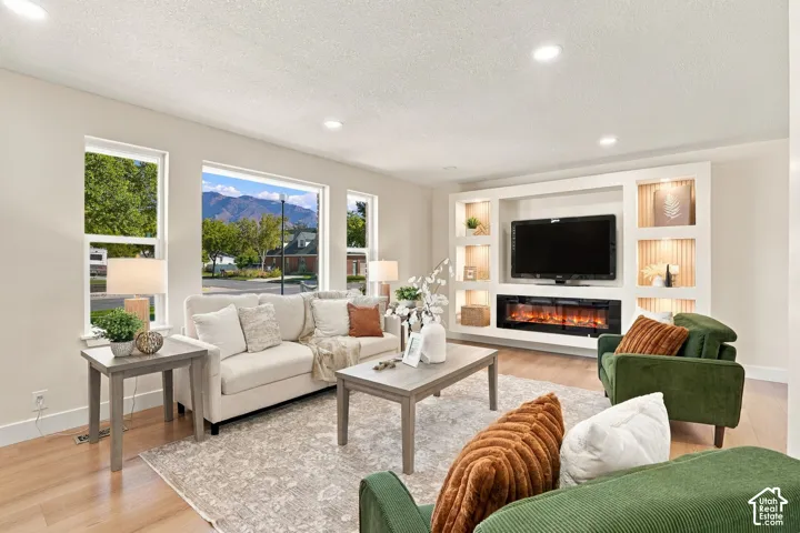 Expansive windows, light wood-finish flooring, recessed lighting, built-in media console, and an electric fireplace