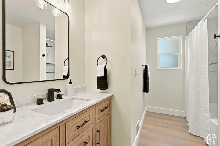 Light wood-finish flooring with a white tub and shower combination