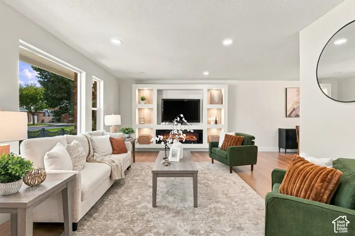 Recessed lighting, wood-finish flooring, built-in media center with illuminated shelving, and an electric fireplace