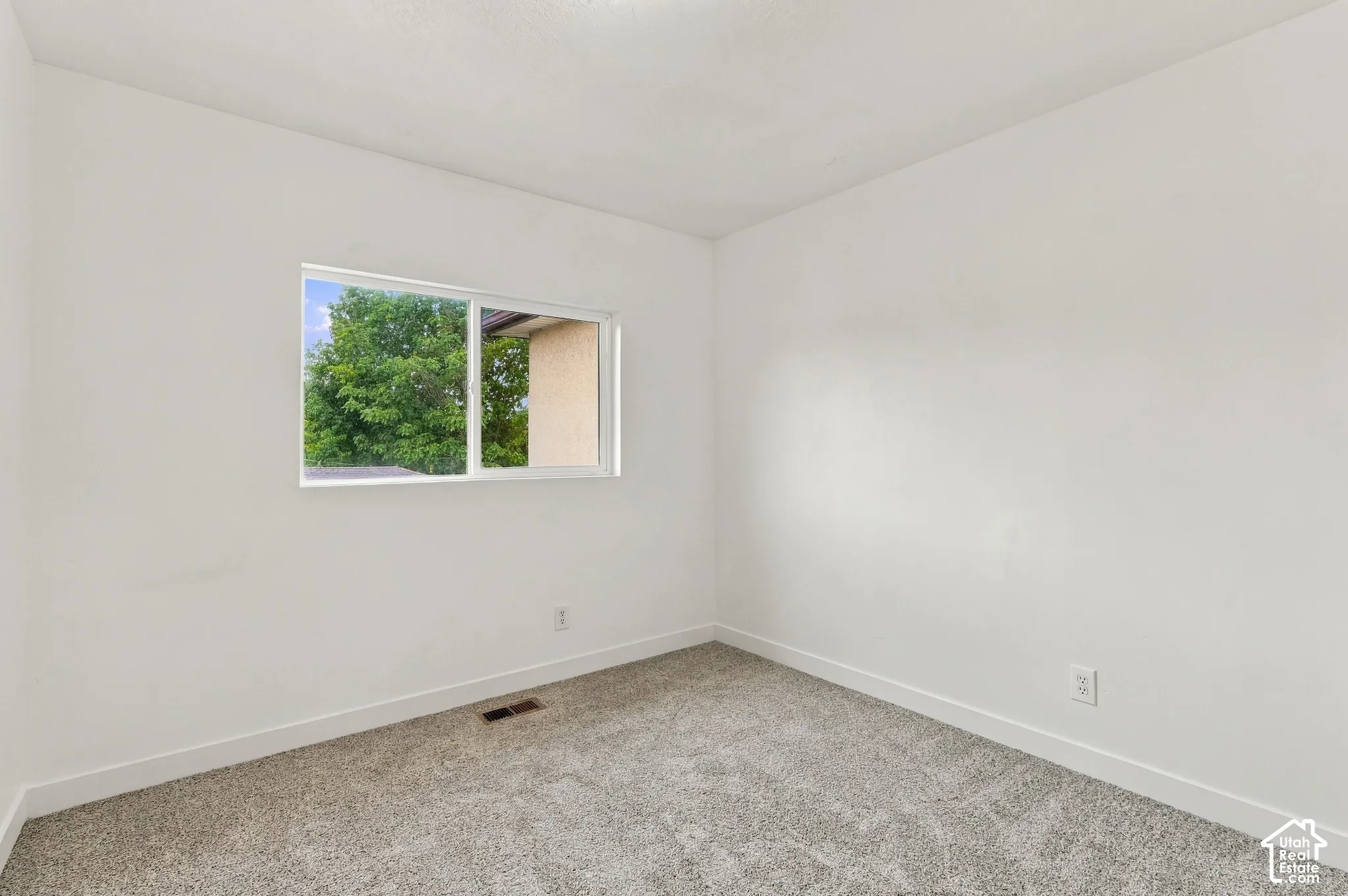 White painted walls with gray carpet flooring and a double-pane window