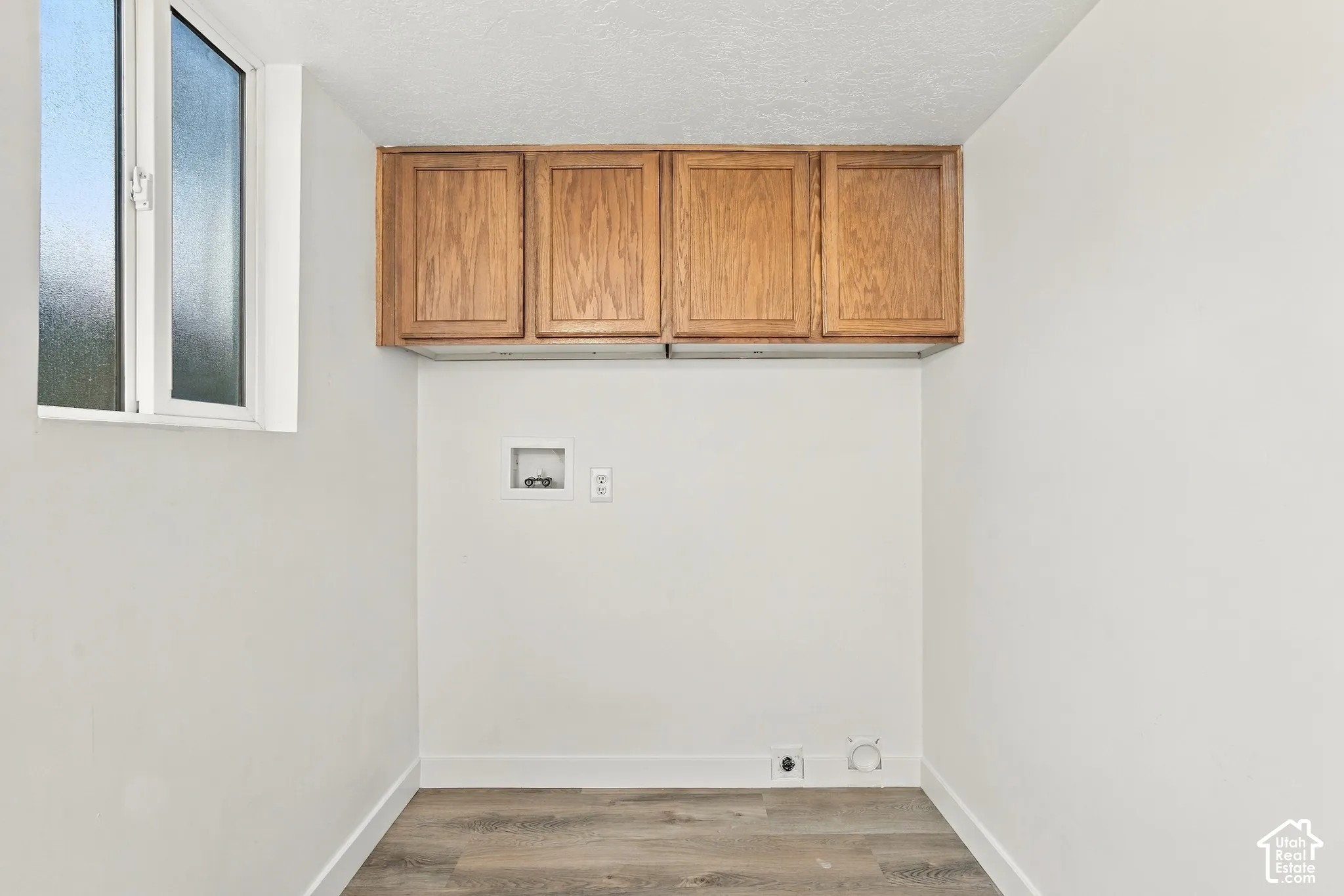 White-framed window, built-in upper cabinetry, wood-finish flooring, and white walls