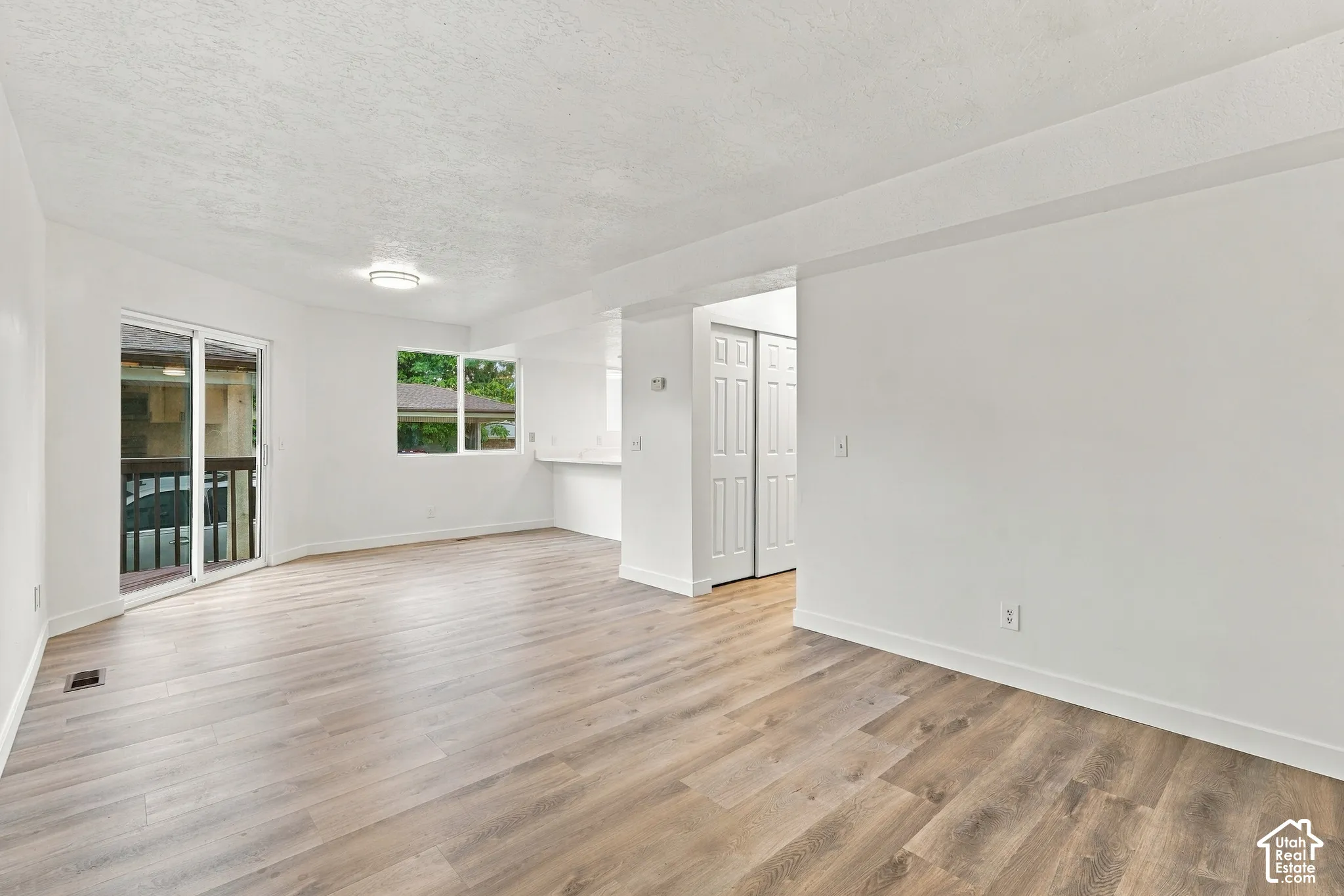 Wood-finish flooring, white walls, sliding glass door, fixed windows, and a built-in counter